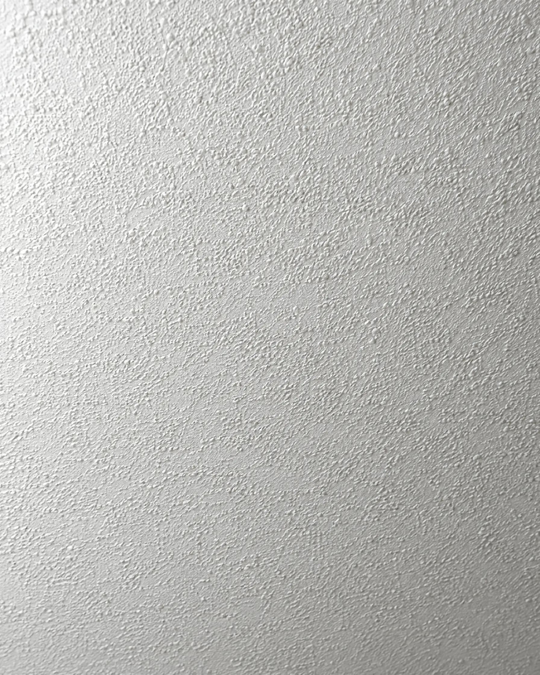 Detail van spachtelputz op een plafond met een fijne, regelmatige korrel